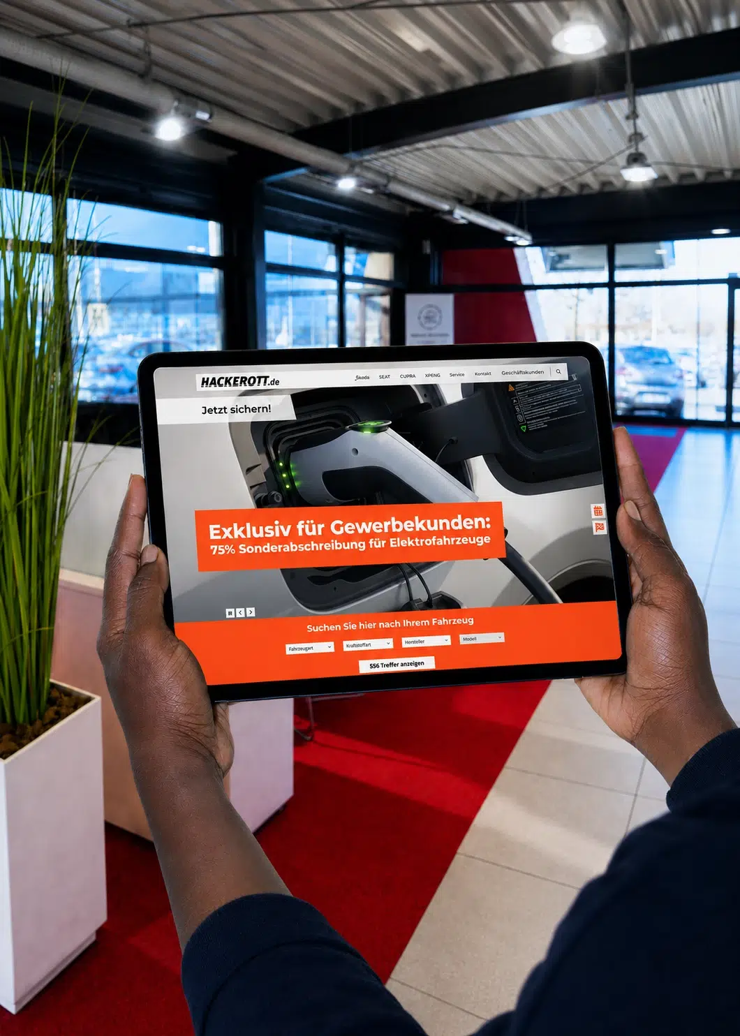 Eine Person hält ein Tablet mit der Hackerott-Website für Elektrofahrzeuge in einem Autohaus.