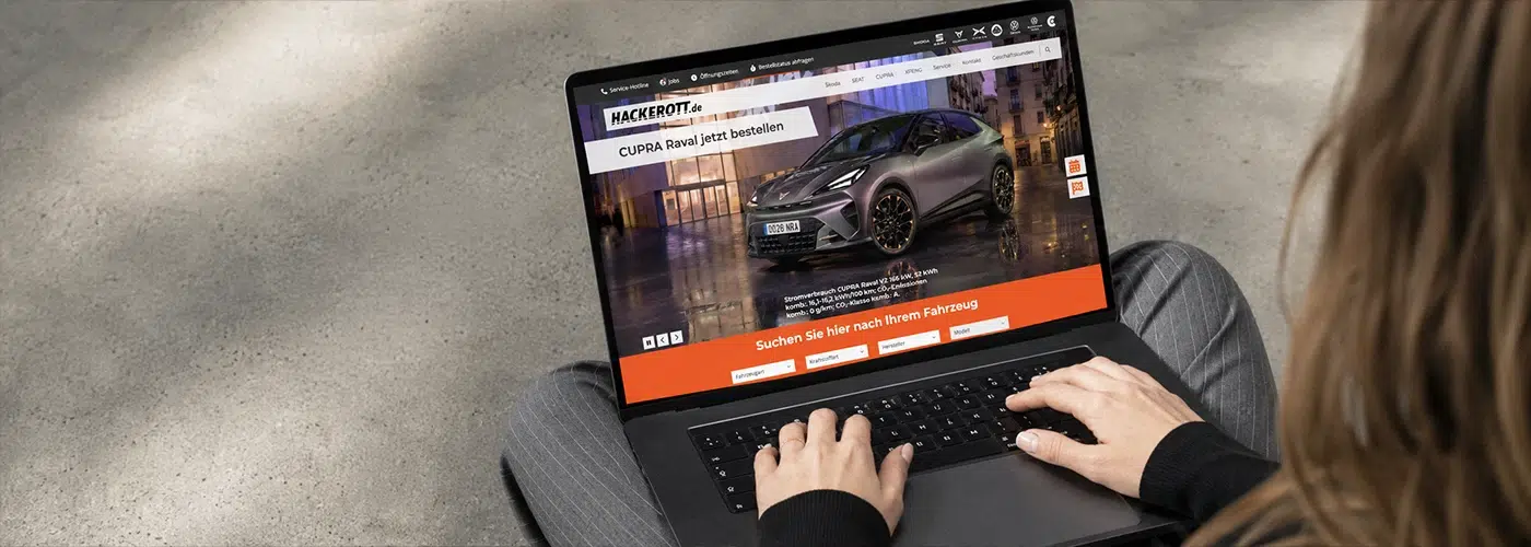 Eine Person nutzt einen Laptop, auf dem die Website des Autohauses Hackerott mit einer Anzeige für den CUPRA Raval geöffnet ist.