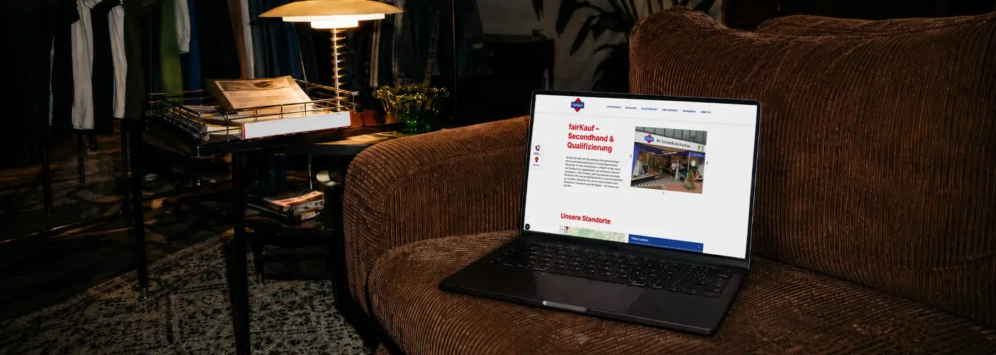 Laptop mit der fairKauf-Website auf einem braunen Cord-Sessel in einem gemütlichen Ambiente.