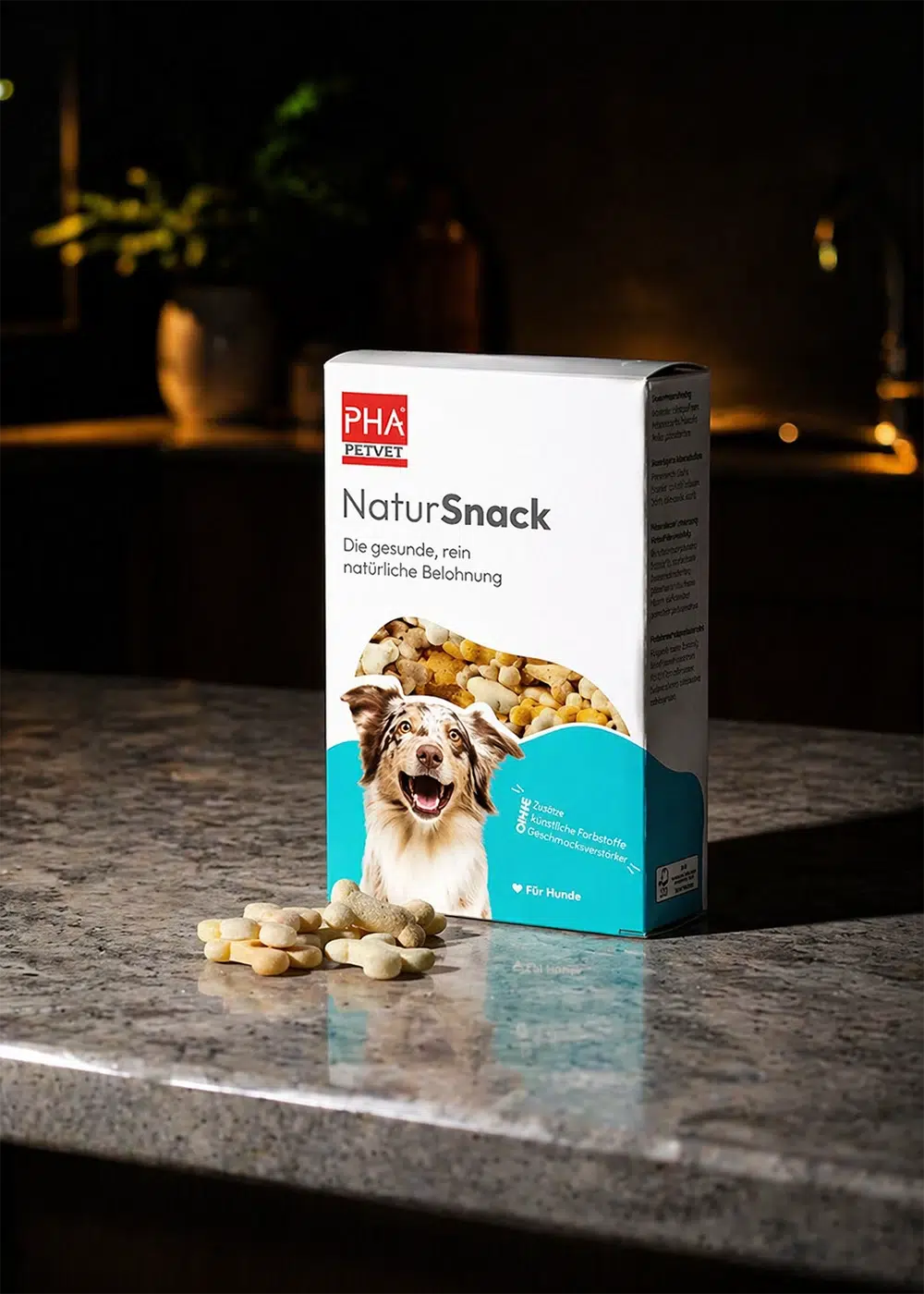 Packung PHA Petvet NaturSnack für Hunde auf einer Küchenarbeitsplatte mit knochenförmigen Leckerlis davor.
