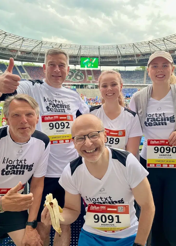 Das lächelnde klartxt racing team mit Startnummern beim B2Run in einem Stadion.