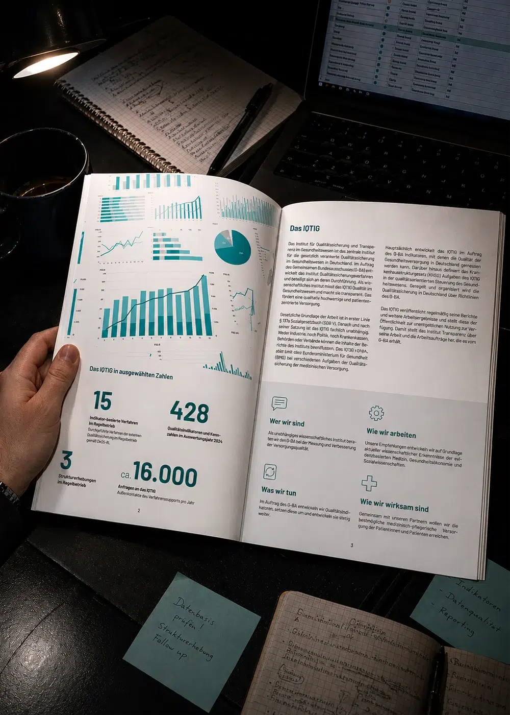 Geöffnete IQTIG-Imagebroschüre mit Infografiken und Kennzahlen auf einem Schreibtisch neben einem Laptop.