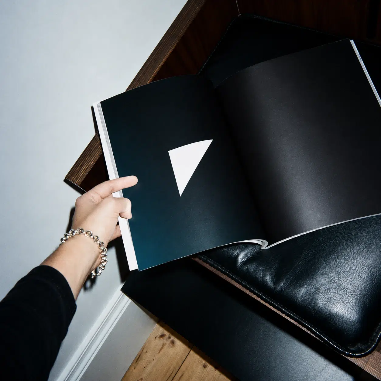 Eine Hand blättert in einem schwarzen Portfolio mit einem weißen Dreieck auf einer Seite.