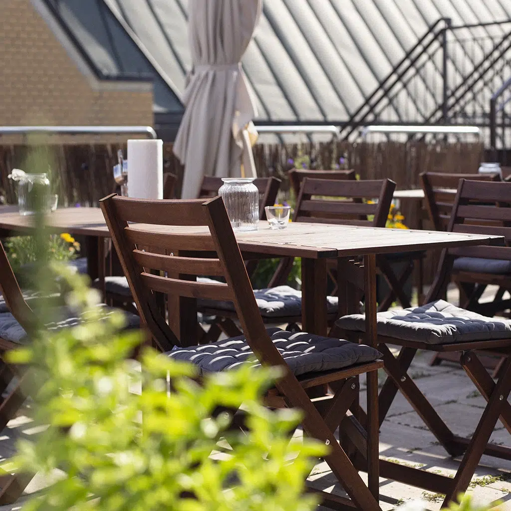 Möblierte Dachterrasse mit Holztischen und Stühlen für Pausen im Freien.