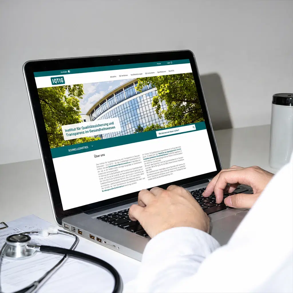 Ein Arzt nutzt die IQTIG-Website auf einem MacBook neben einem Stethoskop.